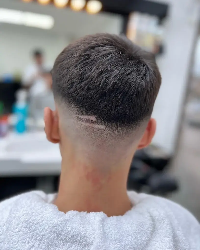 Skin fade with a shaved line detail at the nape, seen from behind, cut at HAWAR BARBER in Darlington