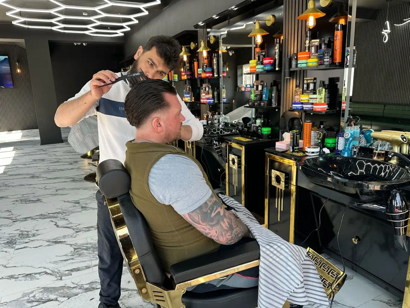 A barber combing a client’s slicked-back hair at the chair at HAWAR BARBER in Darlington