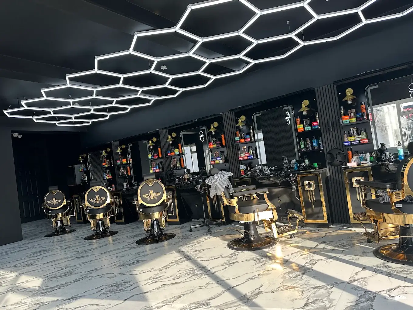 The shop floor at HAWAR BARBER in Darlington: gold-trimmed chairs on a marble floor under the hexagon lights