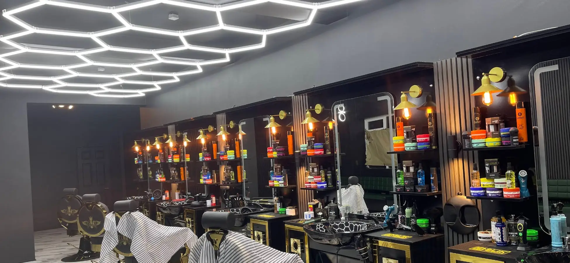 Inside HAWAR BARBER in Darlington: a row of black and gold barber chairs under hexagon ceiling lights